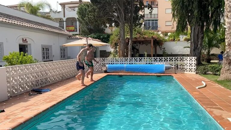 Två män står vid en poolkant och är på väg att hoppa i bassängen.